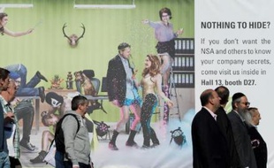 Des visiteurs du Salon high-tech Cebit de Hanovre, en Allemagne, passent devant une publicité pour une société de sécurité informatique, le 10 mars 2014