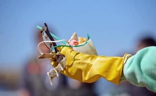 Un homme montre des déchets collectés sur la plage à Biarritz le 22 mars 2013