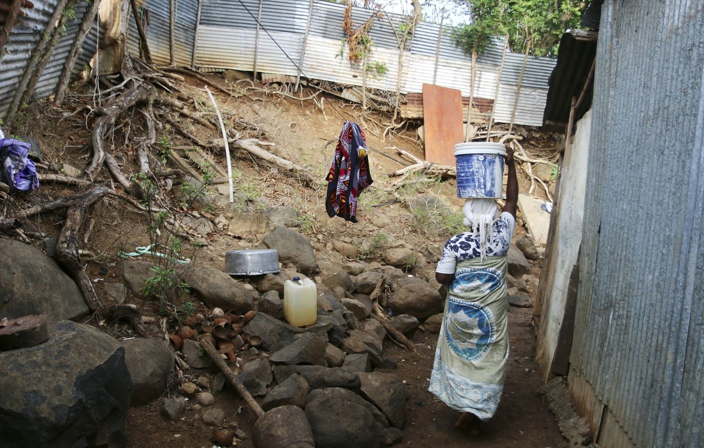 Une femme porte un seau d'eau sur sa tête dans le quartier de M'tsamoudou, près de Bandrele, sur le territoire français de Mayotte dans l'océan Indien, jeudi 12 octobre 2023.