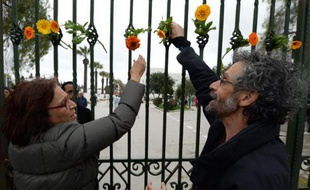 Des Tunisiens accrochent des fleurs le 24 mars 2015 sur les grilles du Musée du Bardo à Tunis, en souvenir des victimes de l'attentat jihadiste qui a fait 21 morts
