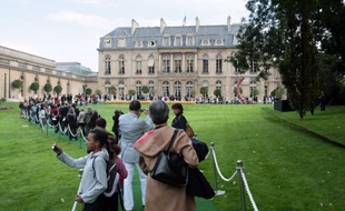 Visitors queue up in the Elysee gardens to visit the Elysee presidential palace on September 19, 2009 at the beginning of the European Heritage Days, which take place on September 19-20. Background at right, a 2004 sculpture by Jean-Baptiste Boiteux and Nicolas Polowski : "C'est ineluctable, il va tomber" (Sure, it will fall down), center, a Charles Henri Fertin work, "22032", displayed for the event. AFP PHOTO JACQUES DEMARTHON