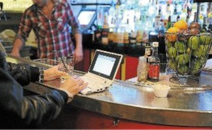 Un consommateur utilise son netbook (mini-PC) dans un café parisien.