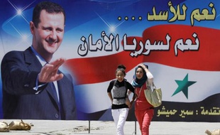De jeunes femmes syriennes passent le 27 mai 2014 devant un portrait de Bachar al-Assad à Damas