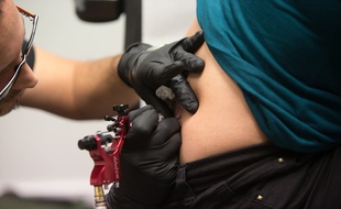 Illustration d'une femme en train de se faire tatouer.
