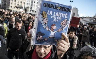 Un homme tient une couverture de Charlie Hebdo sur la laïcité lors d'une manifestation le 11 janvier 2015 à Lyon