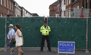 Un agent de police britannique se tient devant une palissade érigée sur Rollestone Street, à Amesbury, le 5 juillet 2018, du fait de l'enquête sur l'empoisonnement d'un couple au Novitchok.