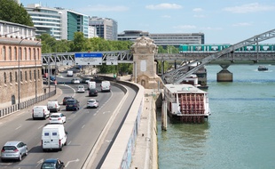 Le 9 juillet 2018, à Paris. Des voitures circulent sur une route à cinq voies, quai de la Rapée (à gauche). Le métro de la ligne 5 passe sur le viaduc d'Austerliz, qui enjambe la Seine.