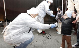 Des experts sanitaires examinent des enfants pour vérifier s'ils montrent des signes de radiation, près de la centrale de Fukushima Daini, à Koriyama, le 13 mars 2011.