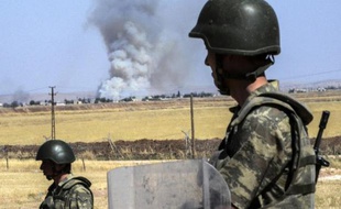 Des soldats turcs observent, par-dessus la frontière avec la Syrie, la fumée des combats dans Kobané, le 25 juin 2015 près de Suruc, en Turquie