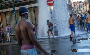 Des enfants jouent dans la rue avec l'eau d'une bouche incendie à Aubervilliers le 30 juin 2015.