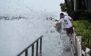 Un homme tente d'éviter une vague le long d'une plage d'Honolulu, alors que l'ouragan Lane approche doucement l'île d'Hawaii, le 24 août 2018.