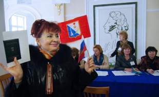 Dans un bureau de vote de Sebastopol, en Crimée, une femme tient le drapeau russe et un bulletin de vote, dimanche 16 mars 2014