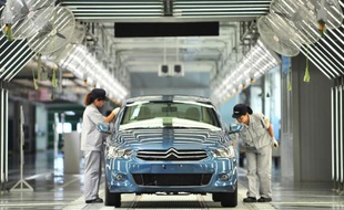 Des employés d'une usine de Dongfeng PSA Peugeot Citroën travaillent dans une usine de Wuhan, en Chine, le 2 juillet 2013