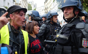 Des manifestantes dont l'une portant un gilet jaune face à des forces de l'ordre, le 31 août 2019 à Paris