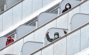 Un passager à bord du bateau de croisière Diamond Princess salue les médias à son arrivée au port de Yokohama le 6 février 2020.