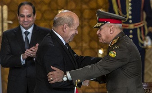 Le ministre français de la Défense Jean-Yves Le Drian (c) serre la main du général egyptien Sedki Sobhi (d), sous les yeux du président, Abdel Fattah al-Sissi, au Caire, le 16 février 2015