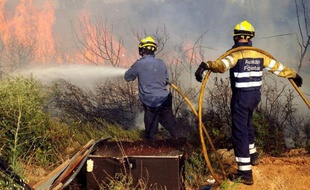 En file sur la route, camions de pompiers et tracteurs se précipitent vers un des foyers de l'incendie: main dans la main, volontaires et pompiers luttent contre le feu qui fait rage en Catalogne, dans le nord-est de l'Espagne.