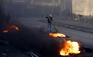 Un Palestinien masqué brûle des pneus lors de heurts avec les forces de sécurité israéliennes, à Chouafat, le 9 octobre 2015 à Jérusalem-Est