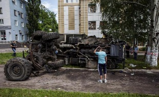 Un Ukrainien examine un véhicule utilisé par les rebelles prorusses et qui a été détruit le 27 mai 2014 par l'armée ukrainienne dans la ville de Donetsk, dans l'est du pays