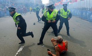 Un coureur est allongé sur le sol, alors que des policiers réagissent après la seconde explosion survenue lors du marathon de Boston