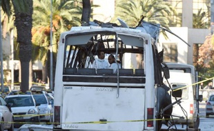 Des enquêteurs de la police scientifique relèvent des indices sur la carcasse d'un bus de la sécurité présidentielle cible d'un attentat à la bombe en plein centre de Tunis, le 25 novembre 2015