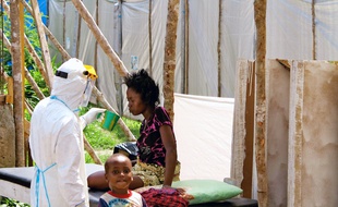 Un travailleur de santé en combinaison de protection soigne une mère et son fils en Sierra Leone, en juillet 2014.
