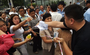 Des proches des passagers chinois du vol MH370 de la Malaysia Airlines font face à la police devant l'ambassade de Malaisie à Pékin, le 7 août 2015.