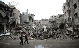 Des enfants passent devant des immeubles détruits dans la zone rebelle de Douma, à l'est de Damas, le 17 novembre 2015 en Syrie.