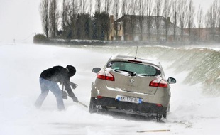 Des personnes tentent de dégager leur voiture bloquée par la neige, le 12 mars 2013 près de Godewaersvelde dans le nord de la France
