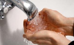 Un homme se lave les mains au robinet.