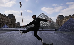 JR devant la pyramide du Louvre lors de l'installation géante de son oeuvre en mars 2019
