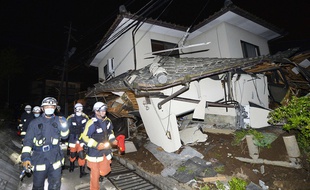 Des pompiers près d'une maison effondrée à Mashiki, dans le département de Kumamoto, après le tremblement de terre qui a secouée le sud-ouest du Japon dans la nuit du 14 au 15 avril 2016.