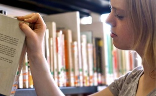 Une jeune femme choisit un livre dans une bibliothèque