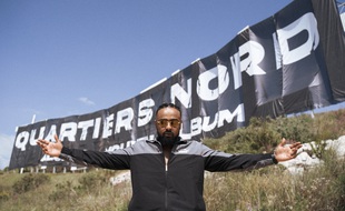 Alonzo devant la bâche annonçant la sortie de son nouvel album, Quartiers nord, le 20 mai prochain.