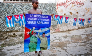 Un enfants cubain porte un poster du président Raul Castro et de son frère Fidelo, le 12 août 2014 à La Havane.