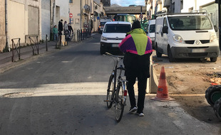 Un cycliste descendu de son vélo, près de la place Salengro, sur le faubourg Figuerolles