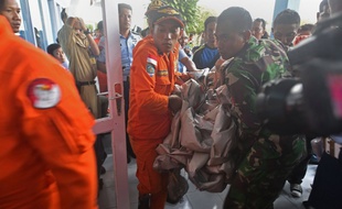 Des secouristes indonésiens apportent des débris de l'A320 d'AirAsia qu'ils viennent de repêcher au large de l'île de Bornéo, au centre de secours dans la capitale de l'île, le mardi 30 décembre 2014.
