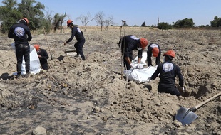 Des casques blancs syriens déterrent des restes humains d'une fosse commune près de Raqa, en Syrie.