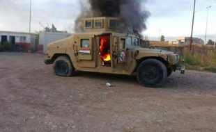 Photo prise d'un véhicule blindé de l'armée irakienne en feu, le 10 juin 2014 à Mossoul, deuxième ville du pays, contrôlée désormais par les jihadistes
