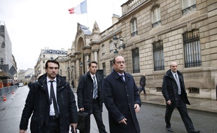 Le président François Hollande escorté par des officiers de police, à la sortie de l'Elysée.