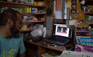Un commerçant d'Athènes regarde l'intervention du Premier ministre Alexis Tsipras, le 1er juillet 2015