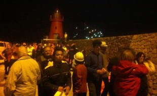 Passagers évacués du "Costa Concordia" arrivant sur l'ile de Giglio la nuit du 13 au 14 janvier 2012 ; les lumières du navire sont visibles en arrière plan.