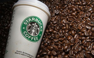 Gobelet de l'enseigne américaine Starbucks au milieu de grains de café le 12 août 2009 à Washington