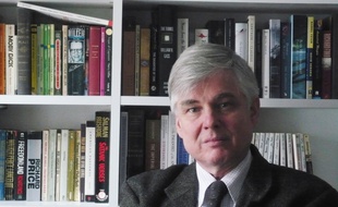 Bernard Genton dans bureau, devant de nombreux ouvrages, en langue anglaise.