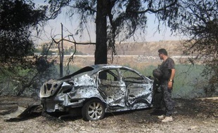 Un membre des forces de sécurité irakiennes inspecte un véhicule carbonisé sur le site d'une attaque à la bombe, à Kirkouk, le 4 juin 2014