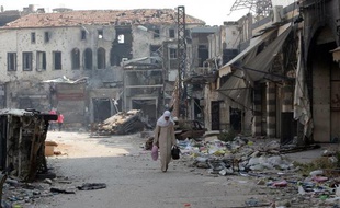 Une femme porte des bagages dans une rue ravagée de Homs, en Syrie, le 12 mai 2014