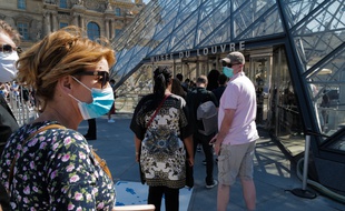 Une femme porte un masque avant d'entrer dans le musée du Louvre