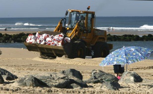 Un tracteur transporte les nombreux sacs poubelles remplis de détritus le 17 juillet 2007 sur la plage de Lacanau (Gironde)