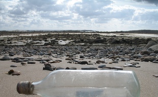 Illustration d'une bouteille posée sur une plage.