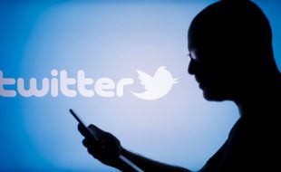 A man looks at a handheld mobile device witht the Twitter logo displayed in the background in this photo illustration in Warsaw, Poland on 06 November, 2022. In a series of messages, Musk engaged with YouTube creators, saying he was planning 